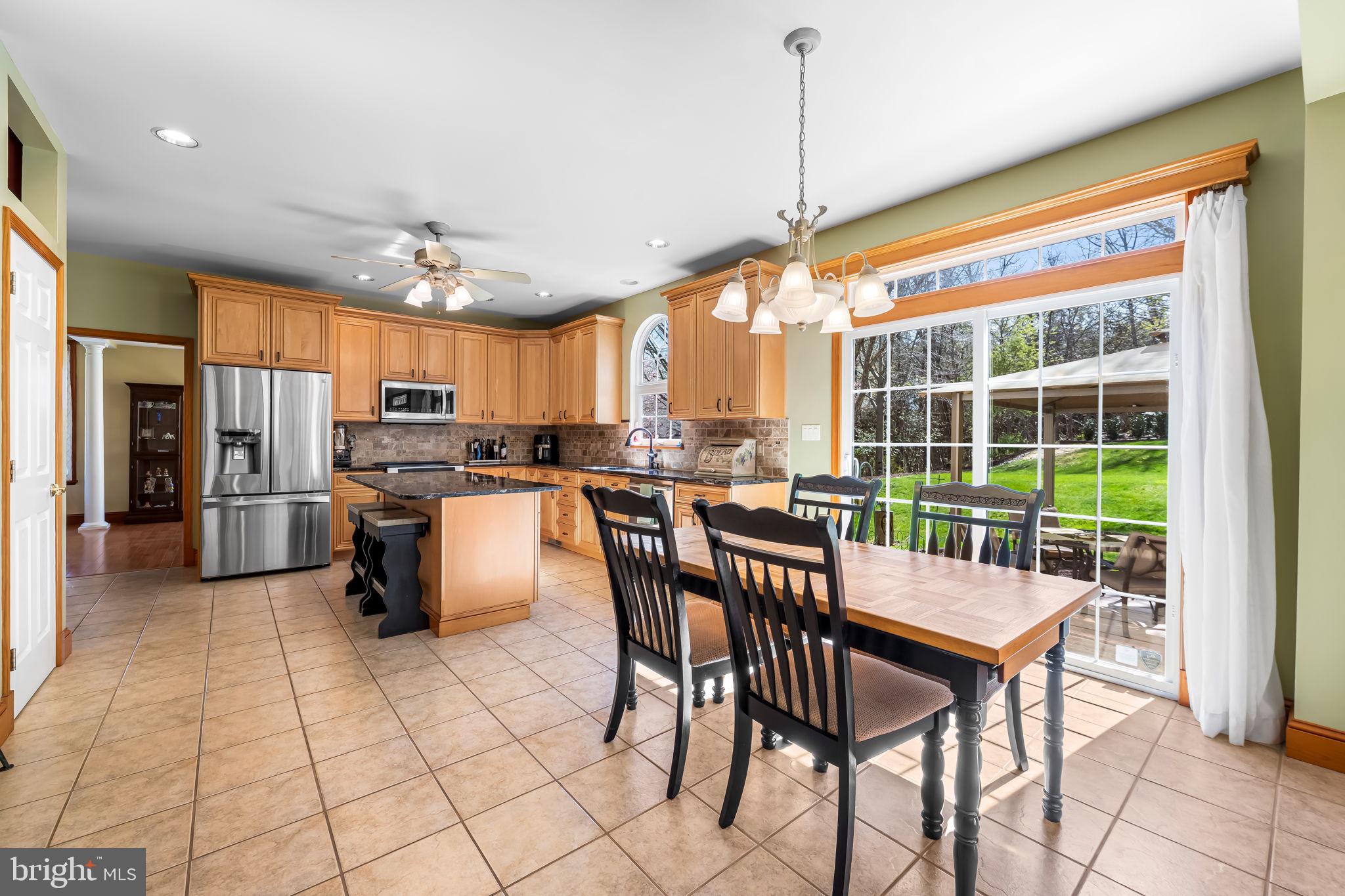 6815 Cherry Tree Court New Market, MD 21774 - Photo 20 of 86 a kitchen with stainless steel appliances kitchen island granite countertop a stove a refrigerator a dining table and chairs with wooden floor