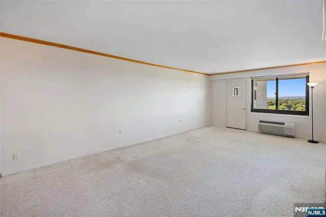 a view of an empty room with a window and a kitchen