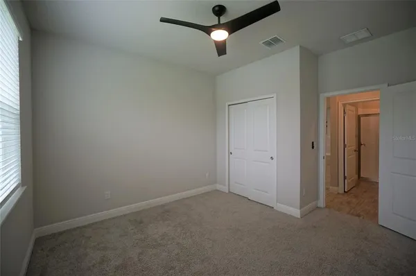 an empty room with ceiling fan and window