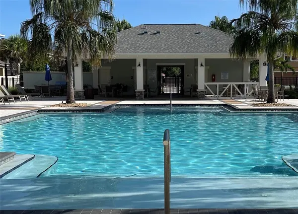 a view of a house with swimming pool and a lawn chairs under palm trees