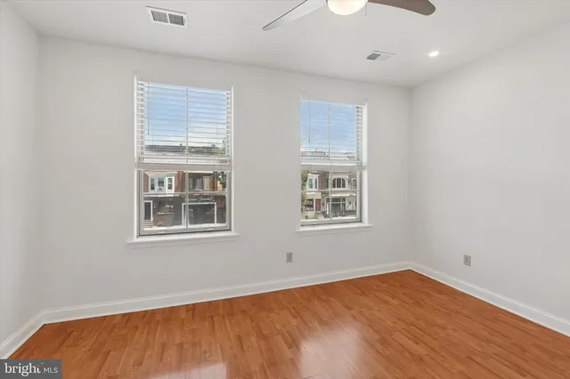 an empty room with wooden floor and windows