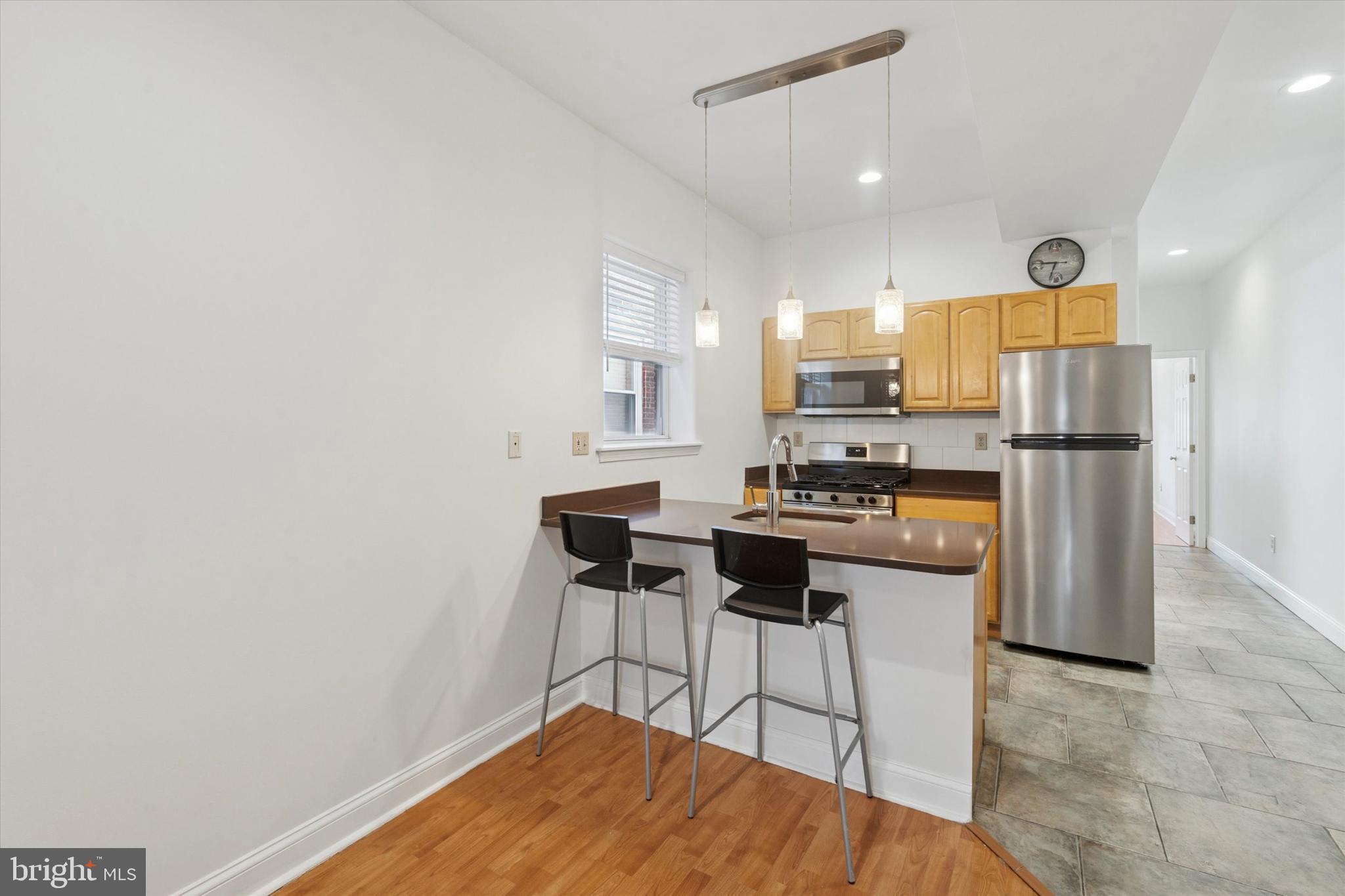 2522-24 South Broad Street, Unit 2F Philadelphia, PA 19145 - Photo 2 of 15 a kitchen with stainless steel appliances a refrigerator a stove a microwave oven with white cabinets and wooden floor