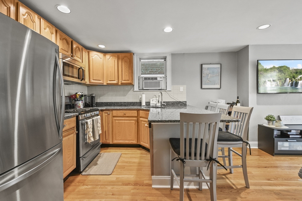 9 Allston Street, Unit 1 Boston, MA 02129 - Photo 6 of 19 a kitchen with stainless steel appliances granite countertop a refrigerator a sink a stove a dining table and chairs with wooden floor