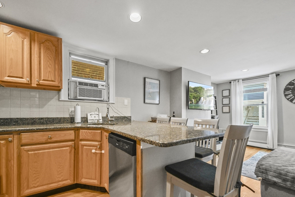 9 Allston Street, Unit 1 Boston, MA 02129 - Photo 8 of 19 a kitchen with granite countertop kitchen island a sink stove and dining table chair