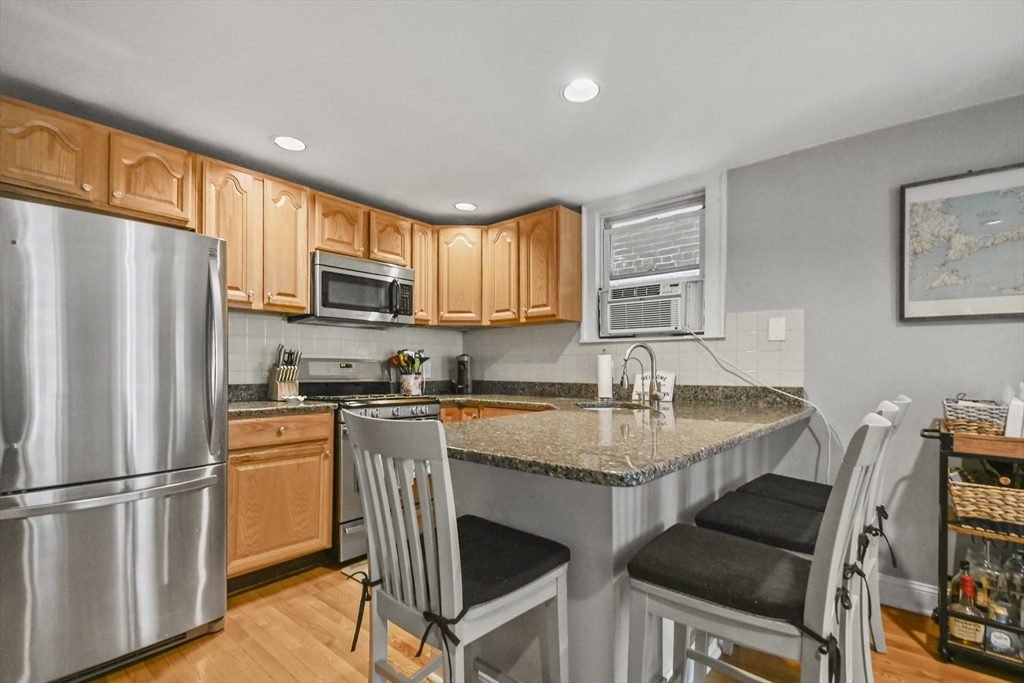 9 Allston Street, Unit 1 Boston, MA 02129 - Photo 9 of 19 a kitchen with stainless steel appliances granite countertop a dining table chairs refrigerator and sink