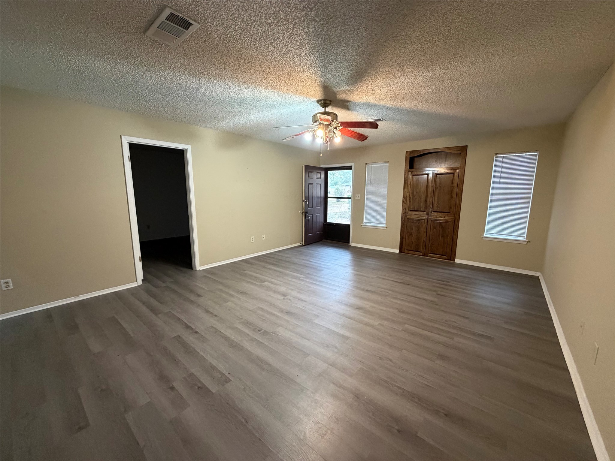 117 Kirk Road Livingston, TX 77351 - Photo 8 of 12 an empty room with wooden floor chandelier fan and windows