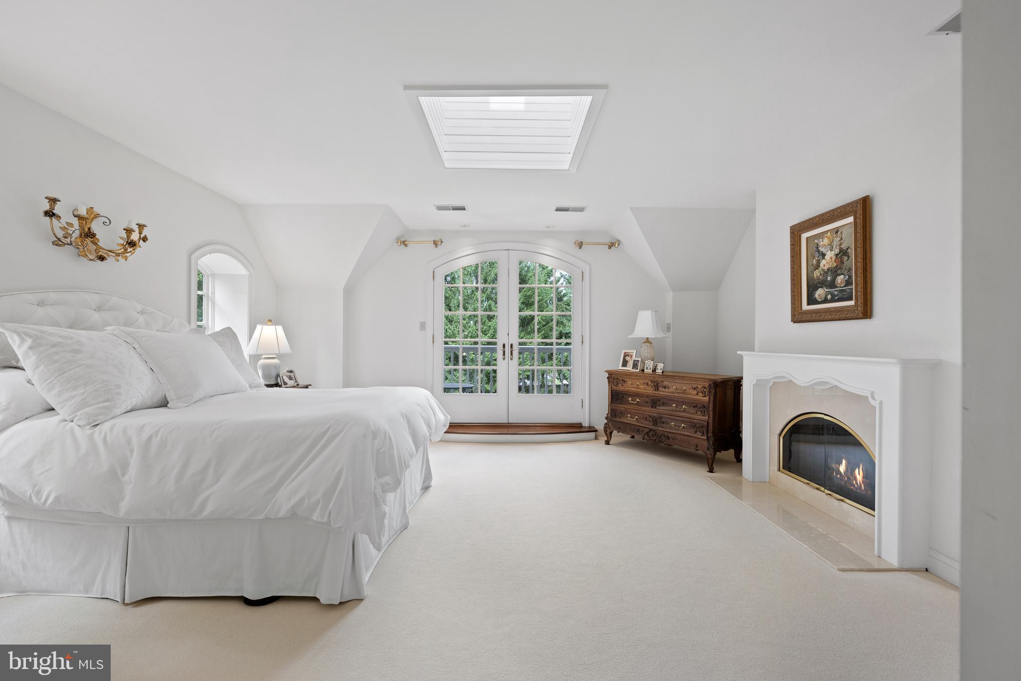 599 Longchamps Drive Wayne, PA 19087 - Photo 22 of 35 a spacious bedroom with a balcony a bed and a fireplace