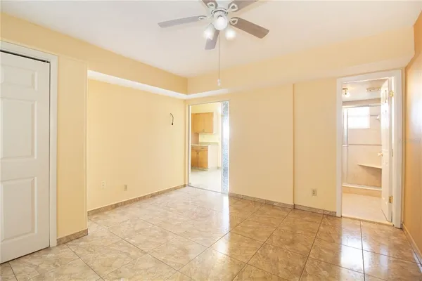 a view of an empty room with cabinet and a ceiling fan
