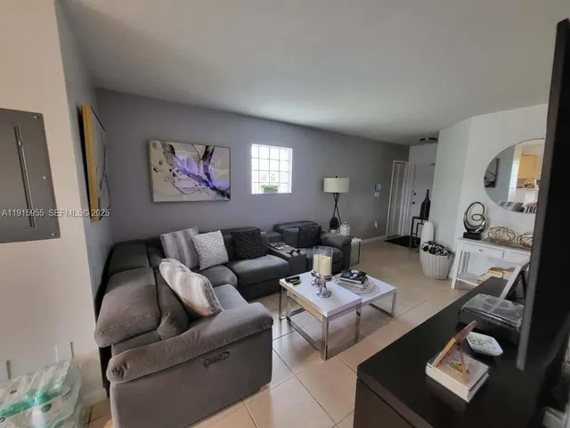 a living room with furniture a flat screen tv and a lamp