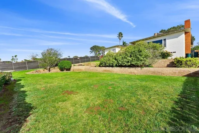 a view of yard with grass & house in the background