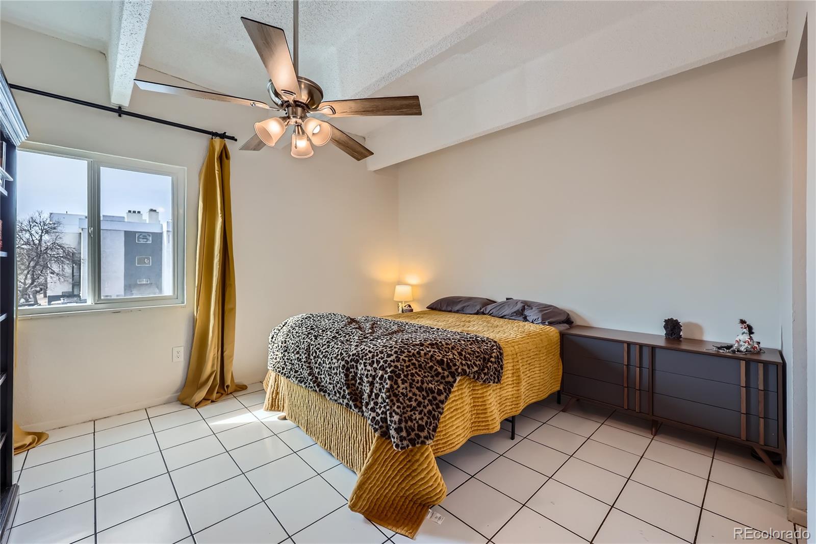 384 South Ironton Street, Unit 314 Aurora, CO 80012 - Photo 6 of 12 a bed sitting in a bedroom next to a window and a chandelier