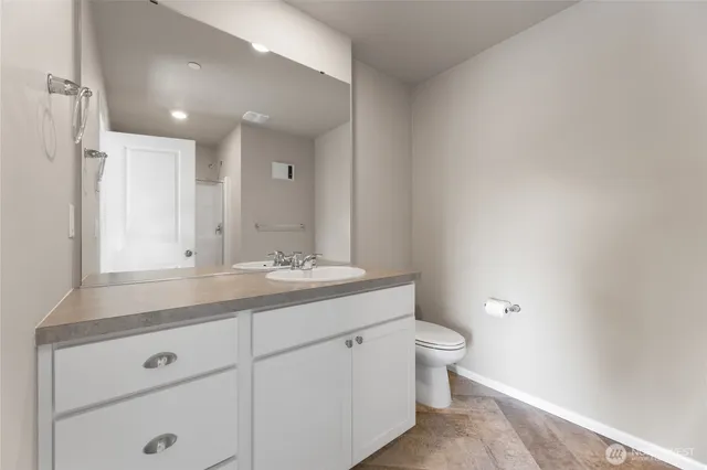 a bathroom with a granite countertop sink a toilet and a mirror