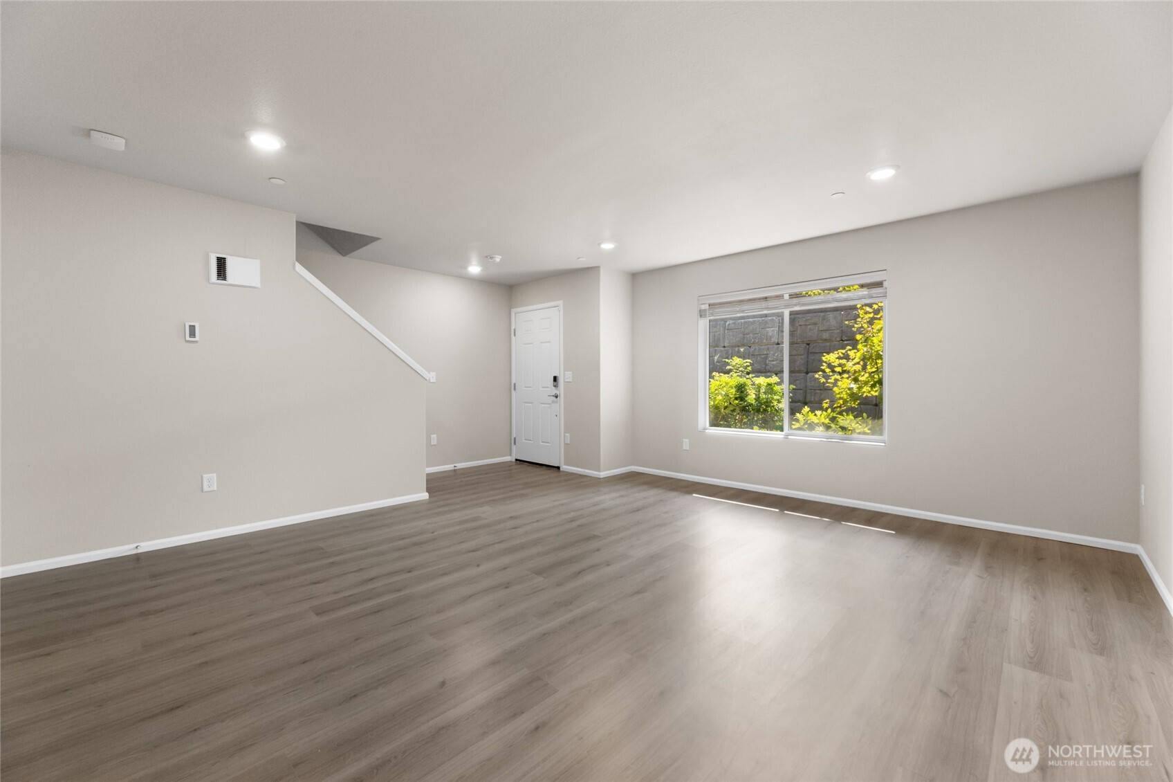 17417 118th Ave Court East, Unit E Puyallup, WA 98374 - Photo 3 of 31 an empty room with wooden floor and windows