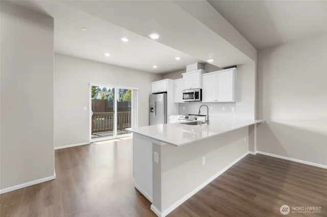 a kitchen with stainless steel appliances a sink stove and wooden floor