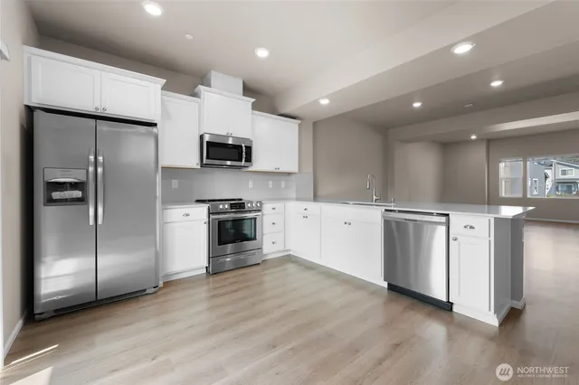 a kitchen with stainless steel appliances kitchen island granite countertop a refrigerator and a stove top oven