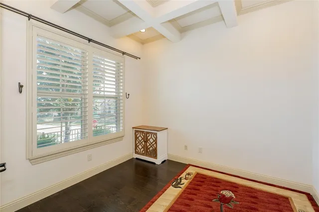 a view of an empty room with a window and hardwood floor