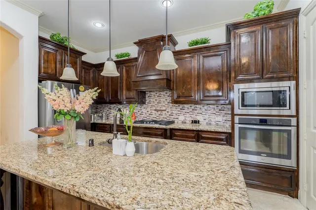 a kitchen with stainless steel appliances granite countertop a sink a stove and a wooden cabinets