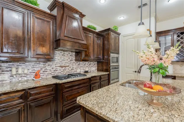 a kitchen with stainless steel appliances kitchen island granite countertop a stove a refrigerator and a sink