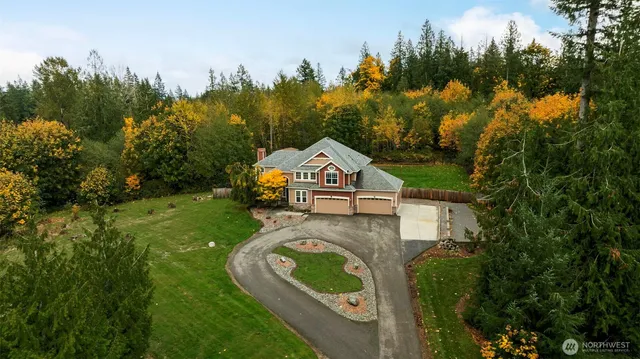 a view of a house with a big yard and large trees