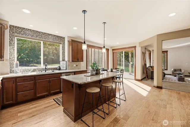 a view of a kitchen with kitchen island granite countertop a sink and a wooden floor
