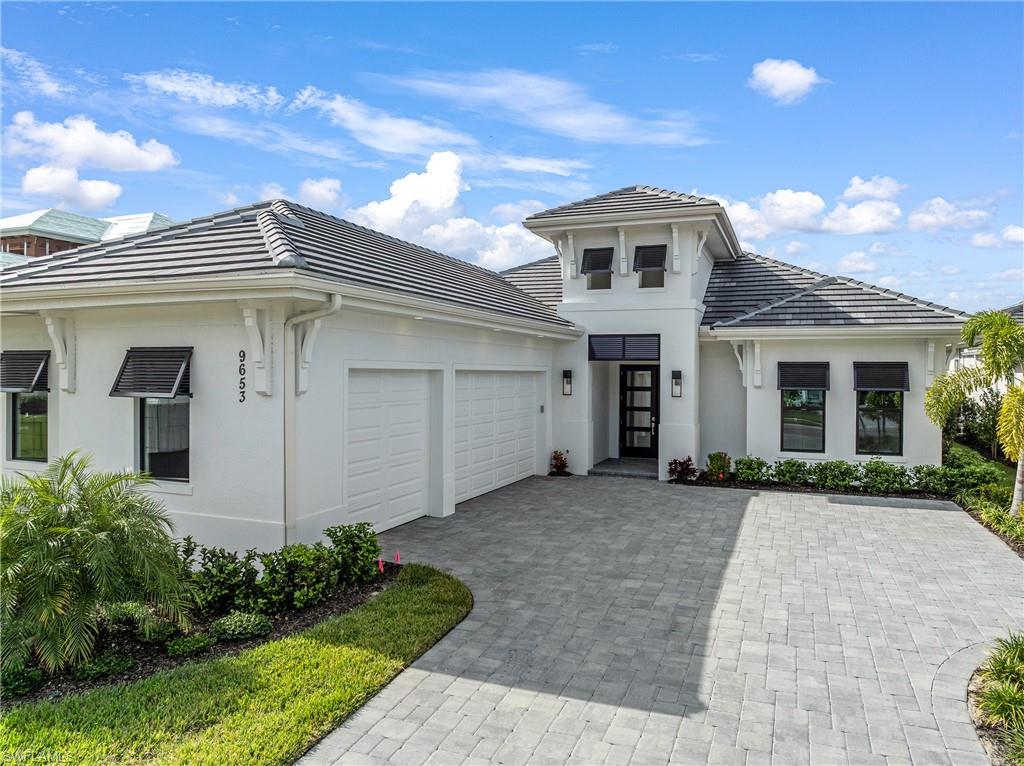 View of front of home with an attached garage, stucco siding, decorative driveway, and a tiled roof