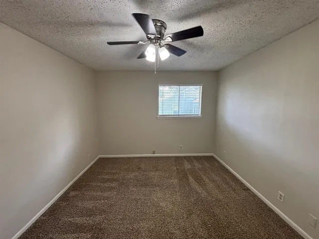 an empty room with window and ceiling fan