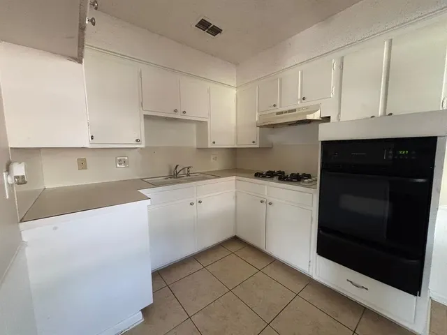 a kitchen with granite countertop white cabinets and black appliances