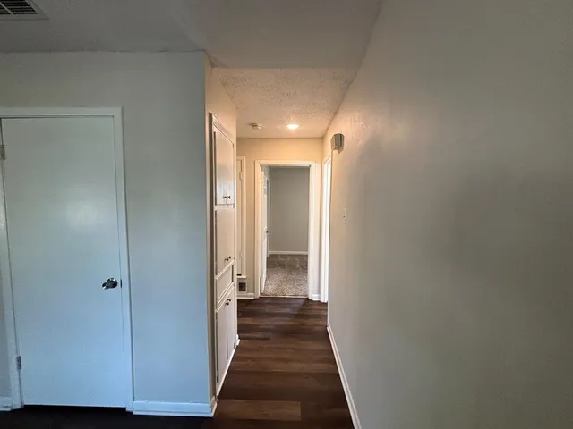 a view of a hallway with wooden floor and closet