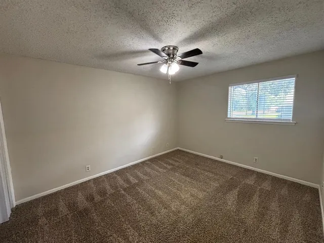 an empty room with windows and fan
