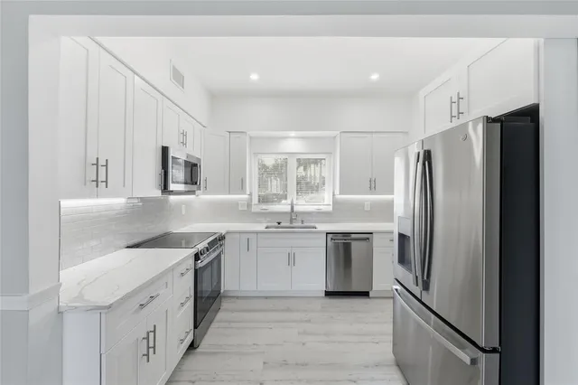 a large kitchen with a sink and stainless steel appliances