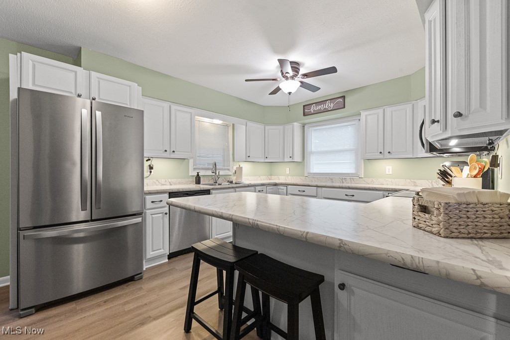 4000 Kenneth Road Stow, OH 44224 - Photo 8 of 50 Kitchen featuring appliances with stainless steel finishes, white cabinetry, a ceiling fan, a peninsula, and light wood-style flooring