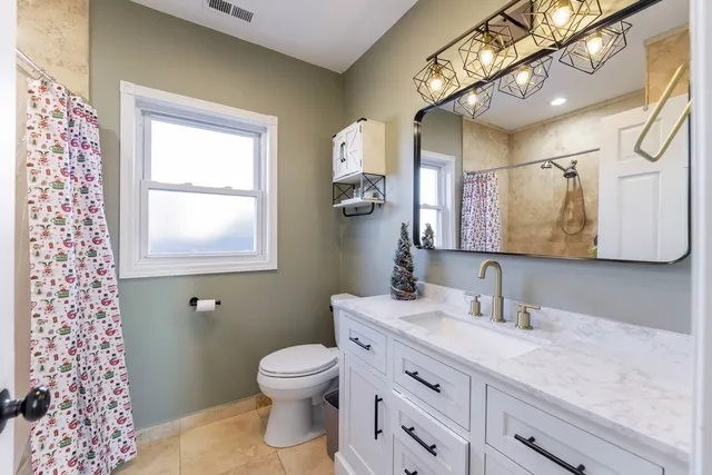 a bathroom with a granite countertop toilet sink and mirror