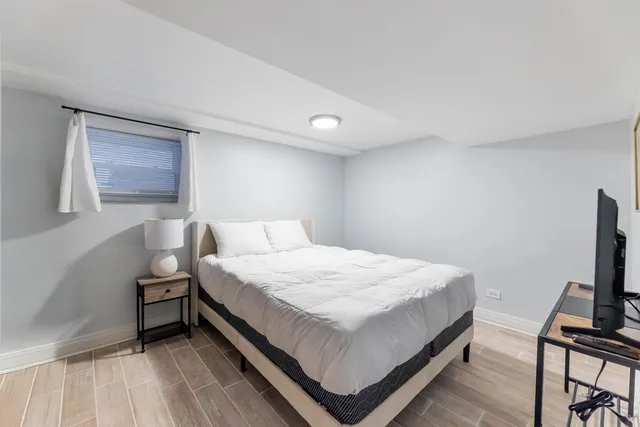 a bedroom with a bed table and a flat screen tv