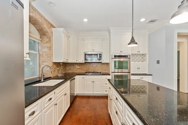 a large kitchen with stainless steel appliances granite countertop a lot of counter space and wooden floors