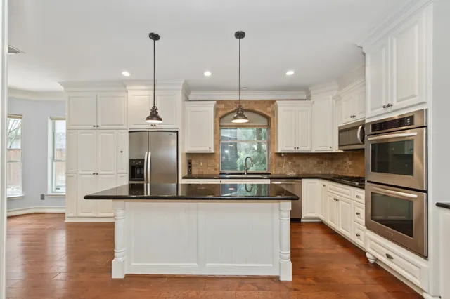a kitchen with stainless steel appliances granite countertop a refrigerator a sink and a stove