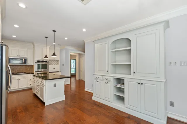 a kitchen with stainless steel appliances kitchen island granite countertop a stove top oven a sink and white cabinets