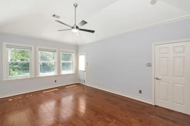 a view of an empty room with a window and wooden floor