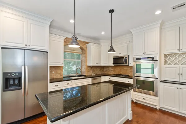 a kitchen with stainless steel appliances granite countertop a sink a refrigerator a stove a microwave and wooden floor