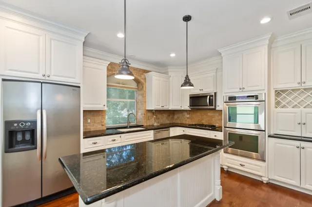 a kitchen with stainless steel appliances granite countertop a sink a refrigerator a stove a microwave and wooden floor