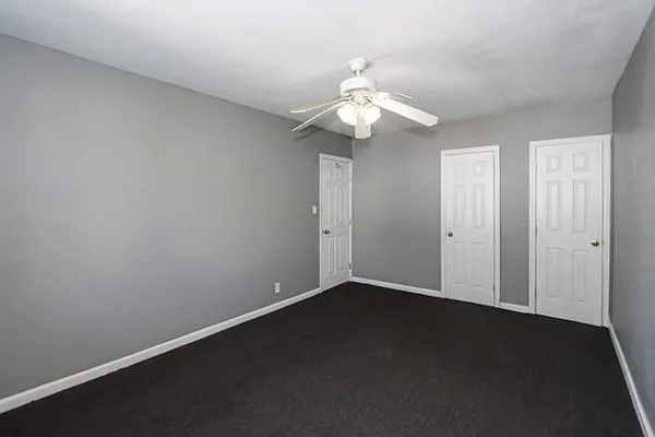an empty room with a chandelier fan and wooden floor
