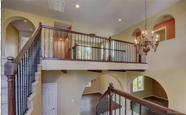 a view of staircase with railing and a chandelier