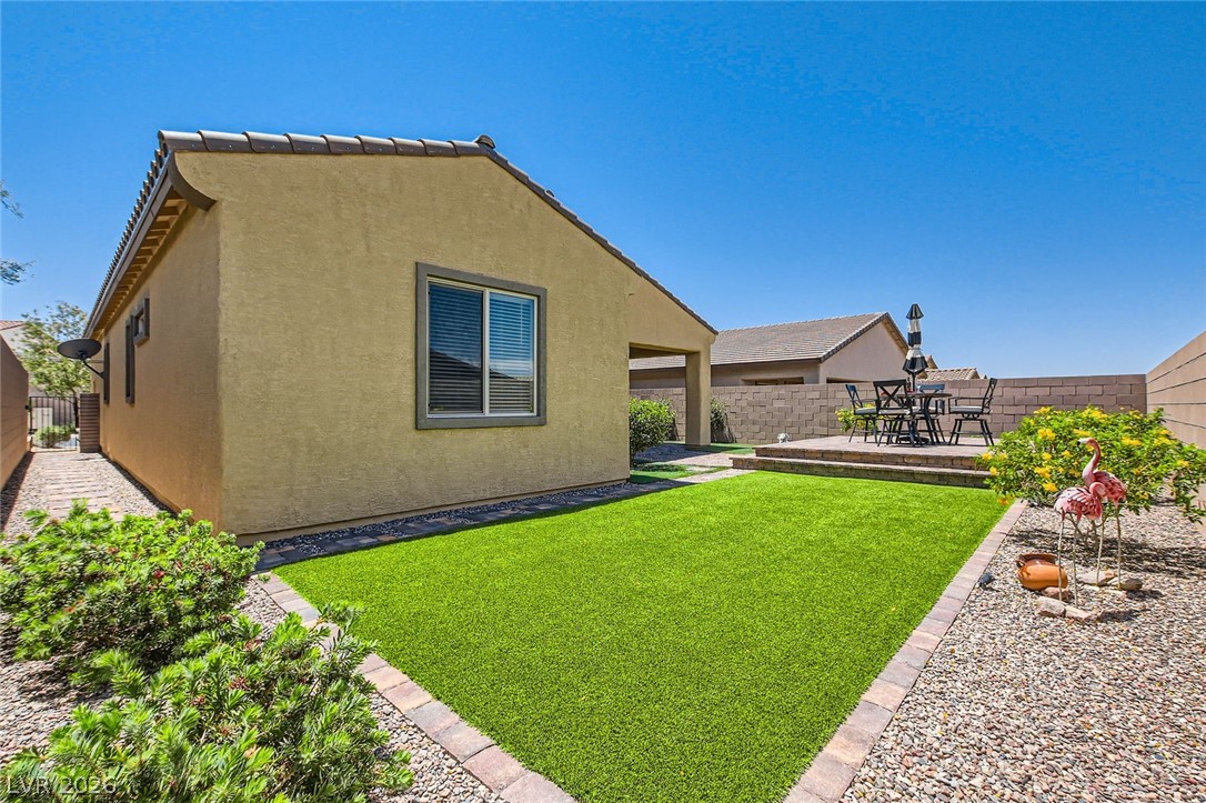498 Pebble Run Avenue Henderson, NV 89011 - Photo 23 of 47 This tranquil backyard offers a comfortable outdoor patio for dining, flanked by low-maintenance turf and xeriscaping.