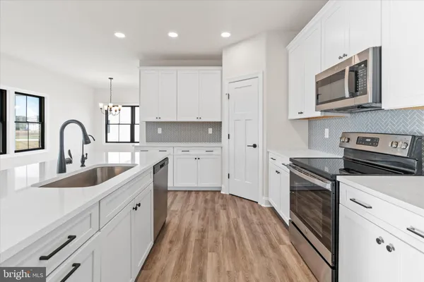 a kitchen with cabinets stainless steel appliances a sink and wooden floor