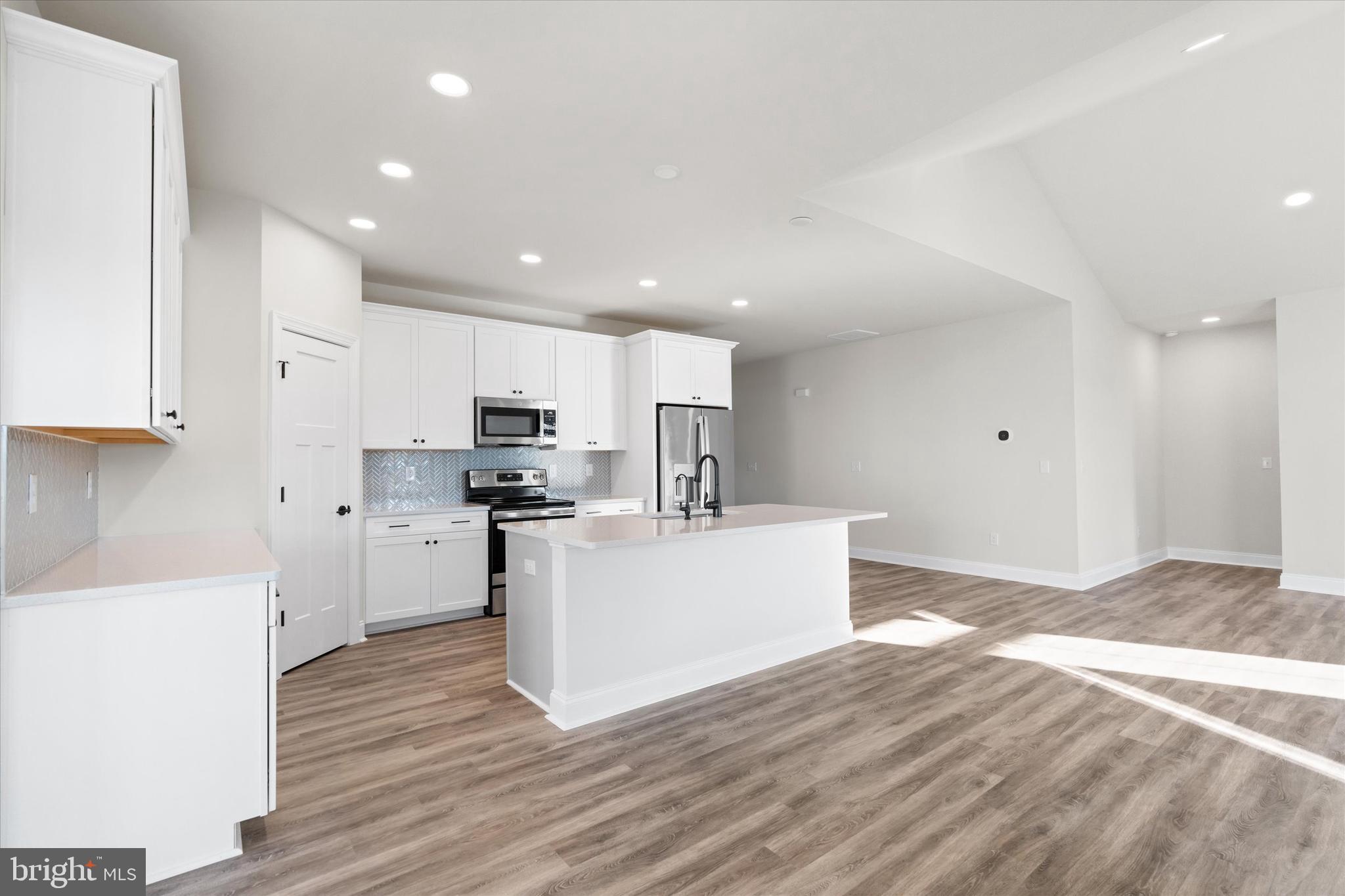 14274 Schooner Run, Unit 83 Ellendale, DE 19941 - Photo 21 of 56 a kitchen with kitchen island a sink a stove a refrigerator and white cabinets