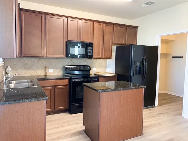 a kitchen with stainless steel appliances granite countertop a refrigerator stove a sink and dishwasher