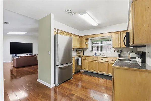 a kitchen with granite countertop a refrigerator stove top oven and sink