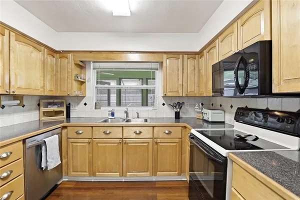a kitchen with stainless steel appliances granite countertop a stove a sink and a microwave