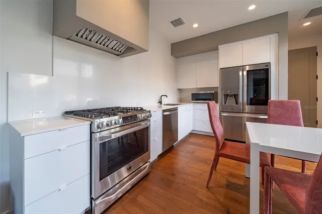 a kitchen with stainless steel appliances kitchen island granite countertop a stove a sink and a refrigerator