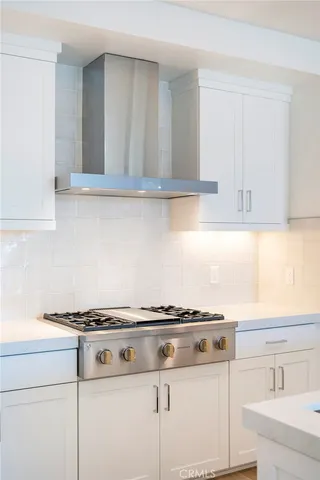 a white kitchen with granite countertop a stove and a sink
