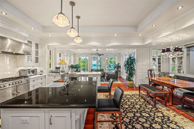 a kitchen with stainless steel appliances granite countertop a stove a sink a dining table chairs and view of living room